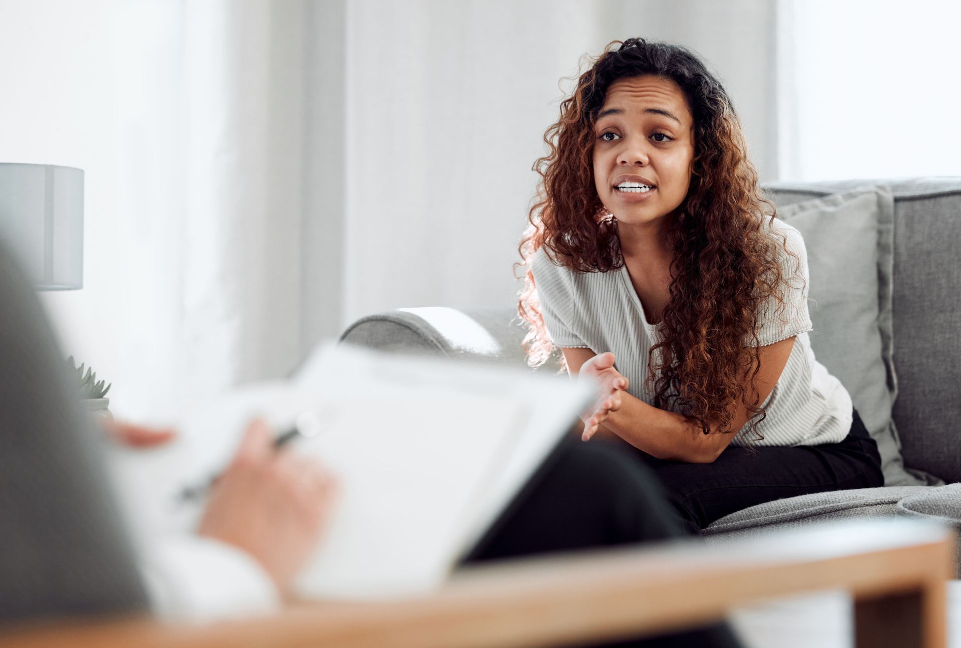 A woman is sitting on a couch talking to a therapist.