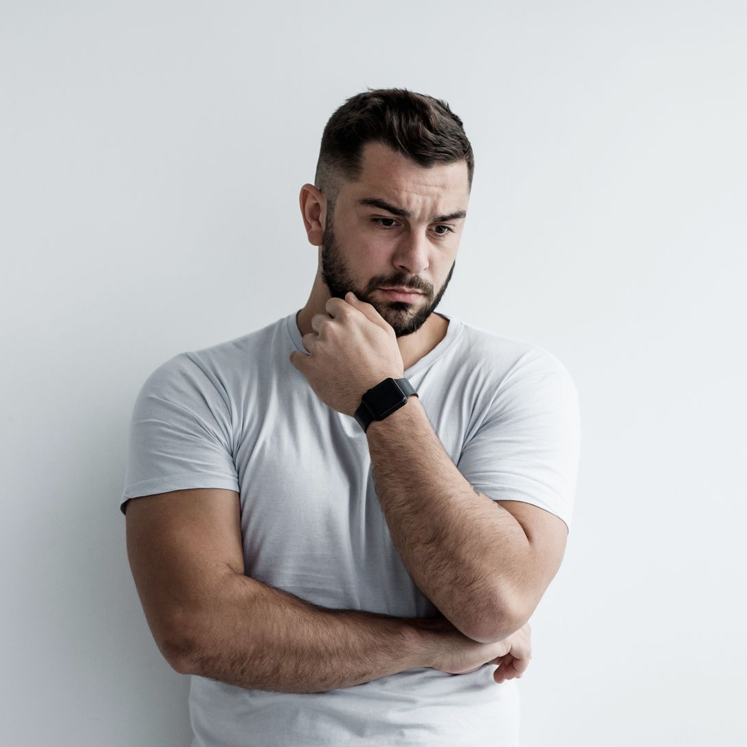 A woman is sitting at a table with her legs crossed and her head resting on her hand.
