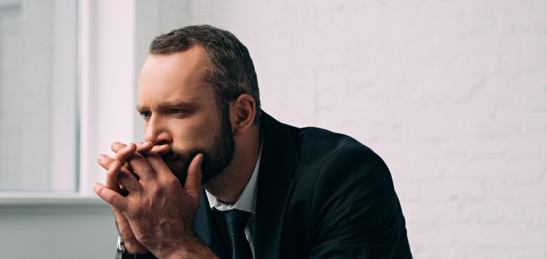 A woman is covering her face in front of a mirror.