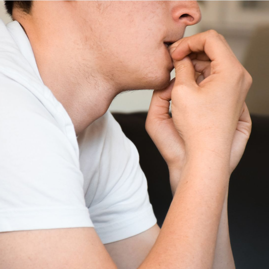 A man with his hand on his head looking out a window