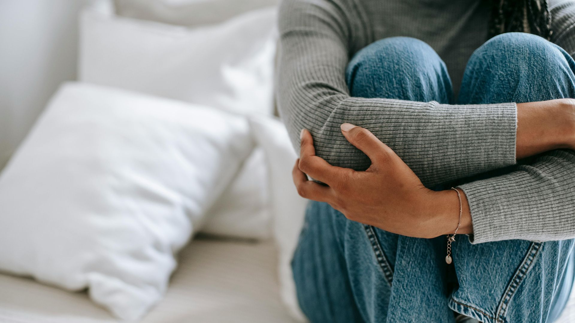 A woman is sitting on a couch with her legs crossed.