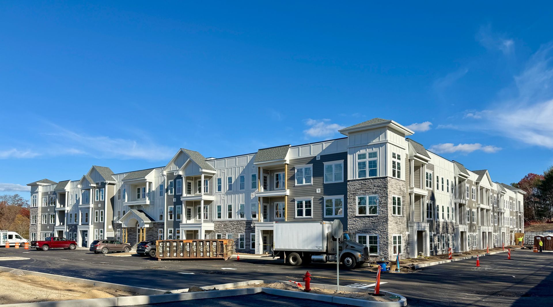 Multi-story apartment building under construction; blue and white exterior, blue sky.