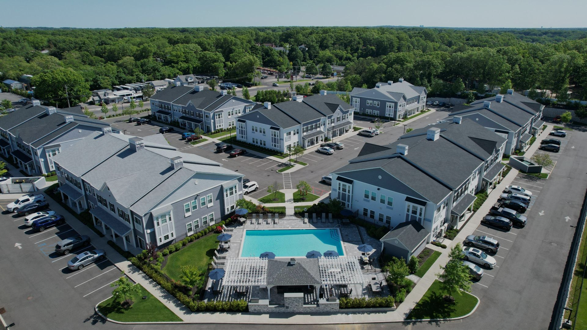 Outdoor seating area with gravel path and lounge furniture on a grassy yard surrounded by trees.
