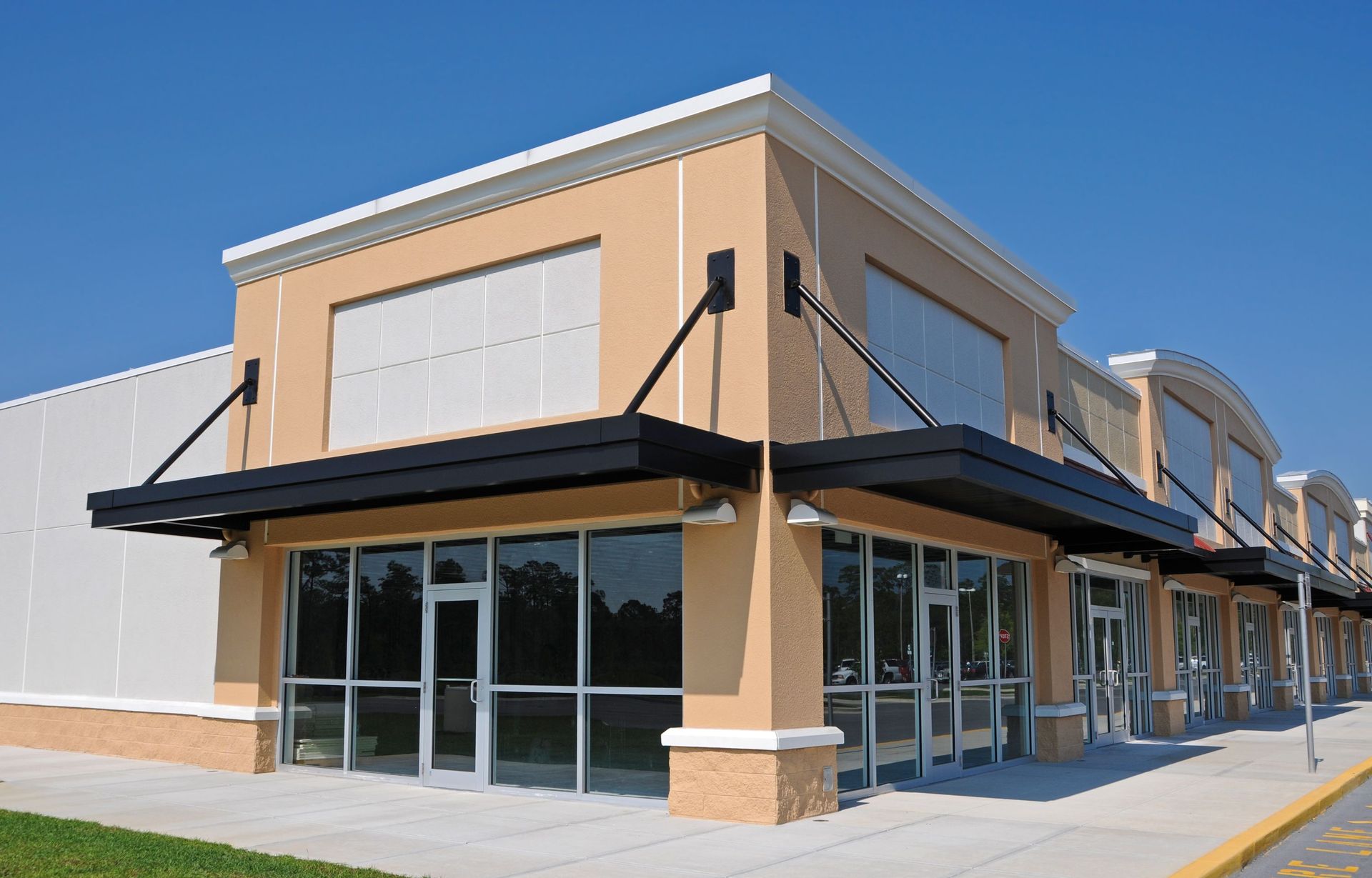 Corner storefront in a beige strip mall with black awnings and large glass windows.