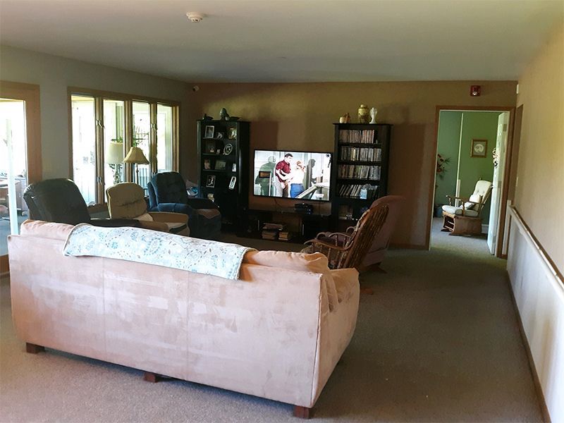 A living room with a pink sofa, TV, bookshelves, chairs, and an open doorway.