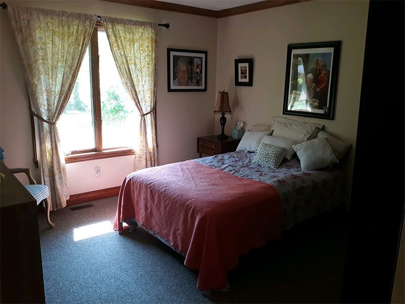 Bedroom with a bed, window with curtains, and artwork on the wall.