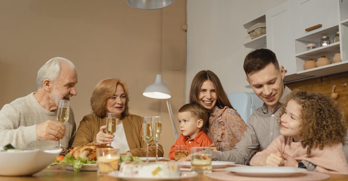 Family at a dining table, toasting with drinks. Includes a child, senior adults, and middle-aged adults smiling.