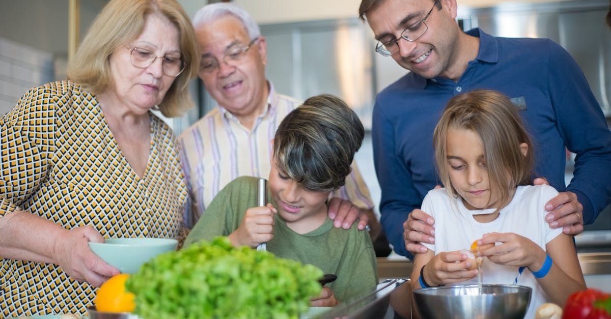 Family cooking together in a kitchen, looking at the food.