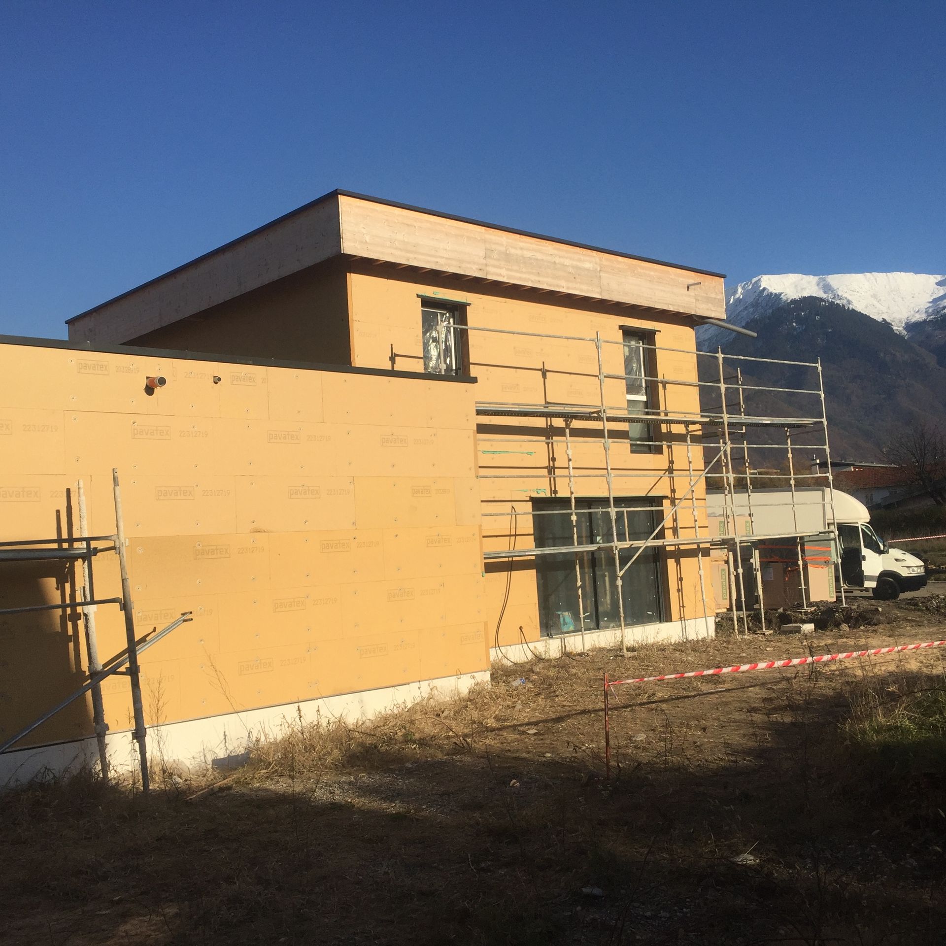Un bâtiment jaune entouré d'échafaudages et de montagnes en arrière-plan