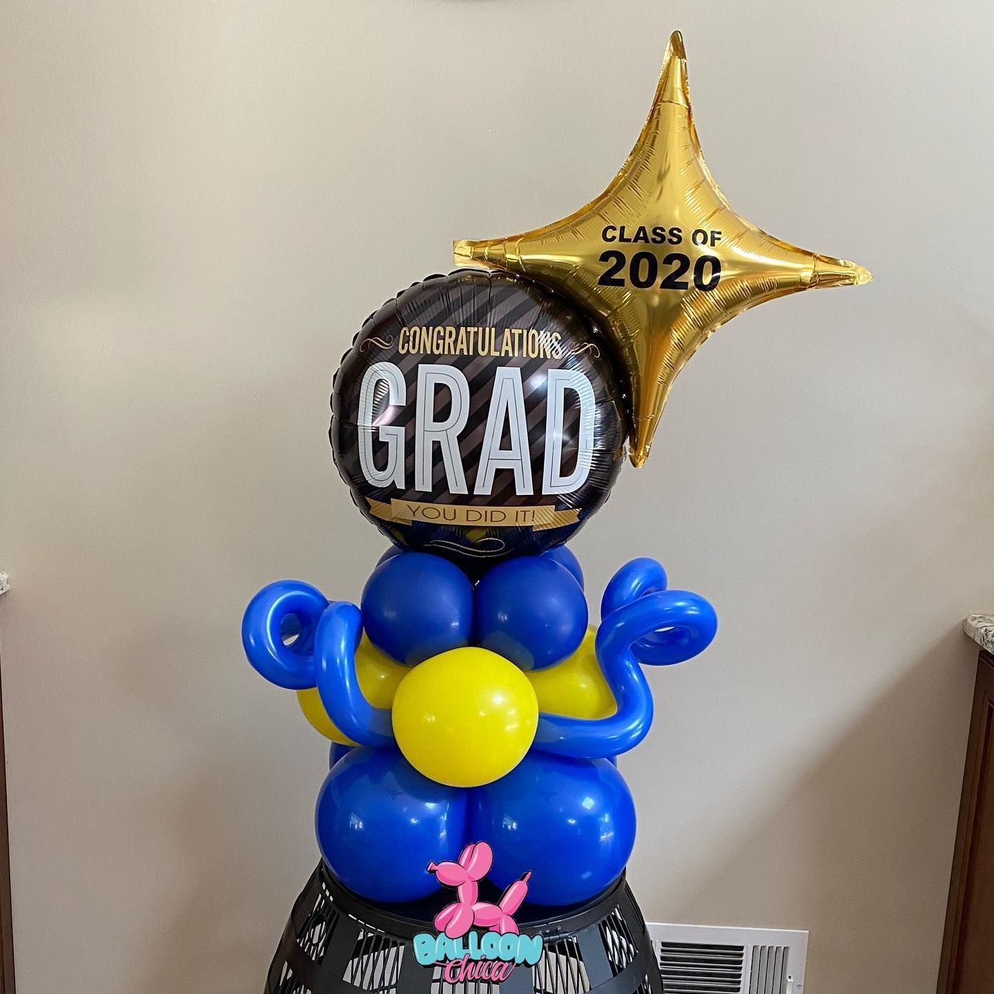 a stack of blue and yellow balloons with a graduation balloon on top
