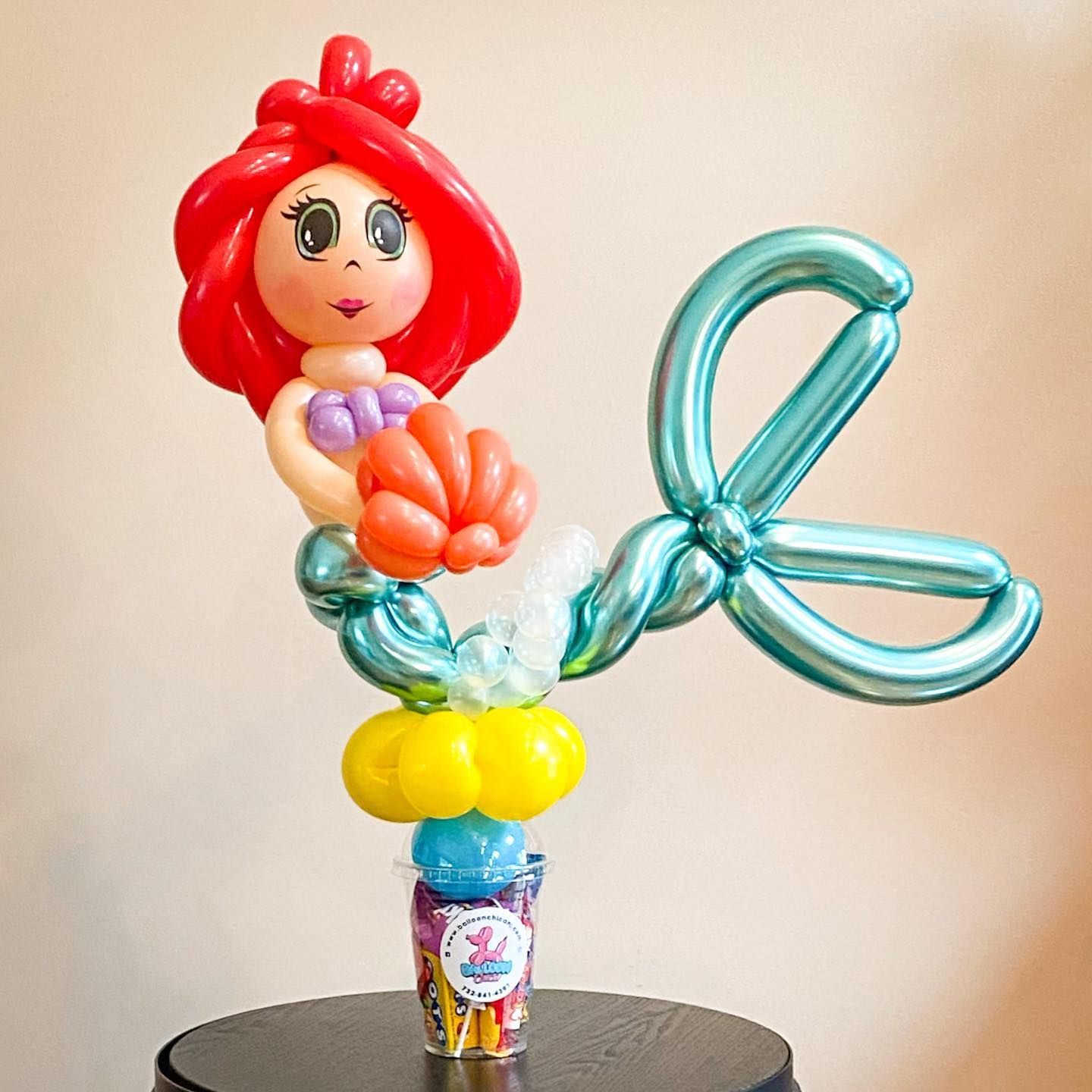 a mermaid made out of balloons is sitting on a table
