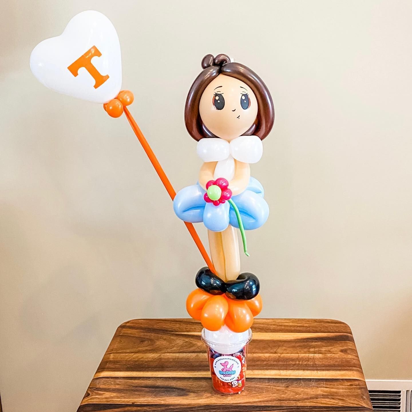 a balloon doll is holding a heart shaped balloon with the letter i on it
