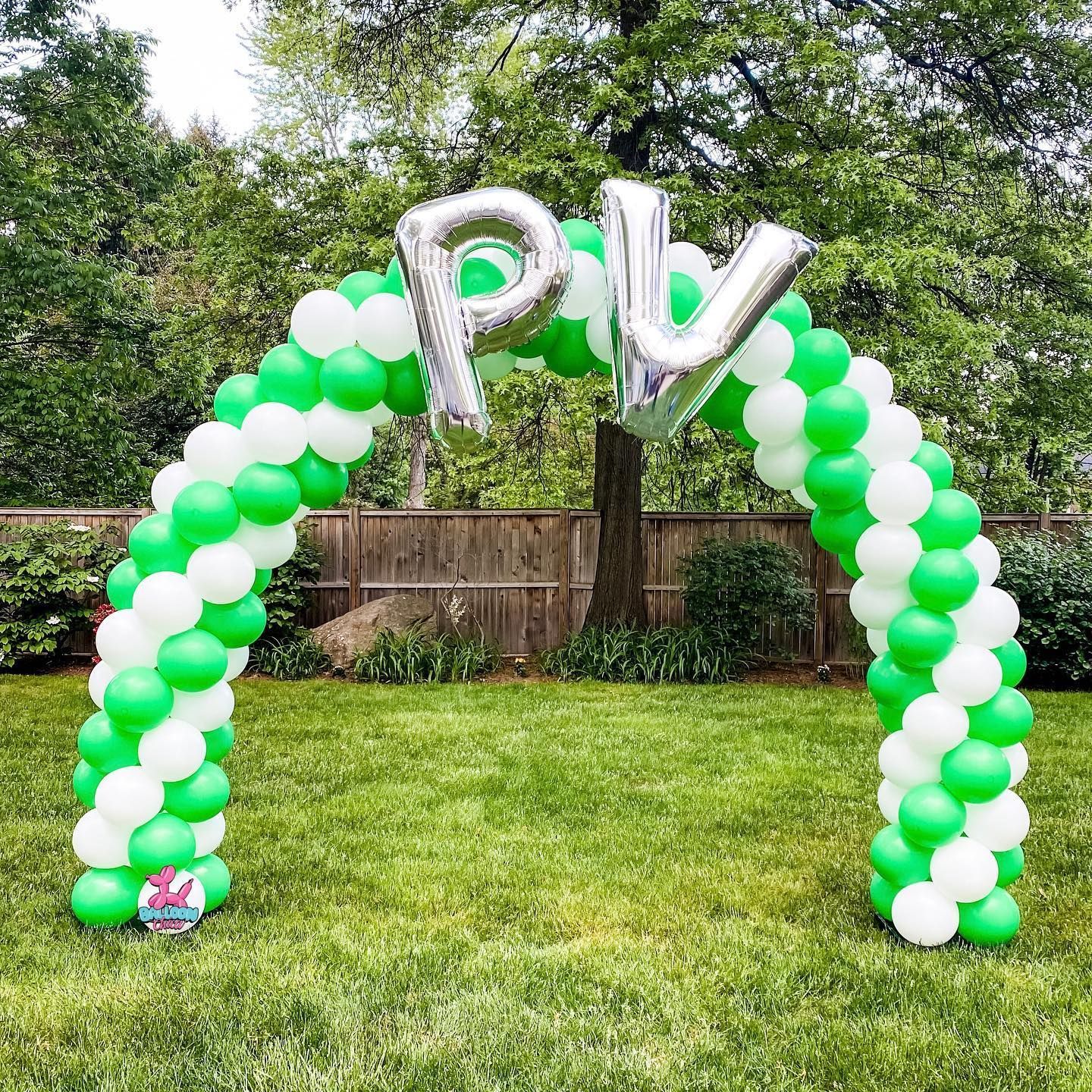 a green and white balloon arch with the letters pv on it
