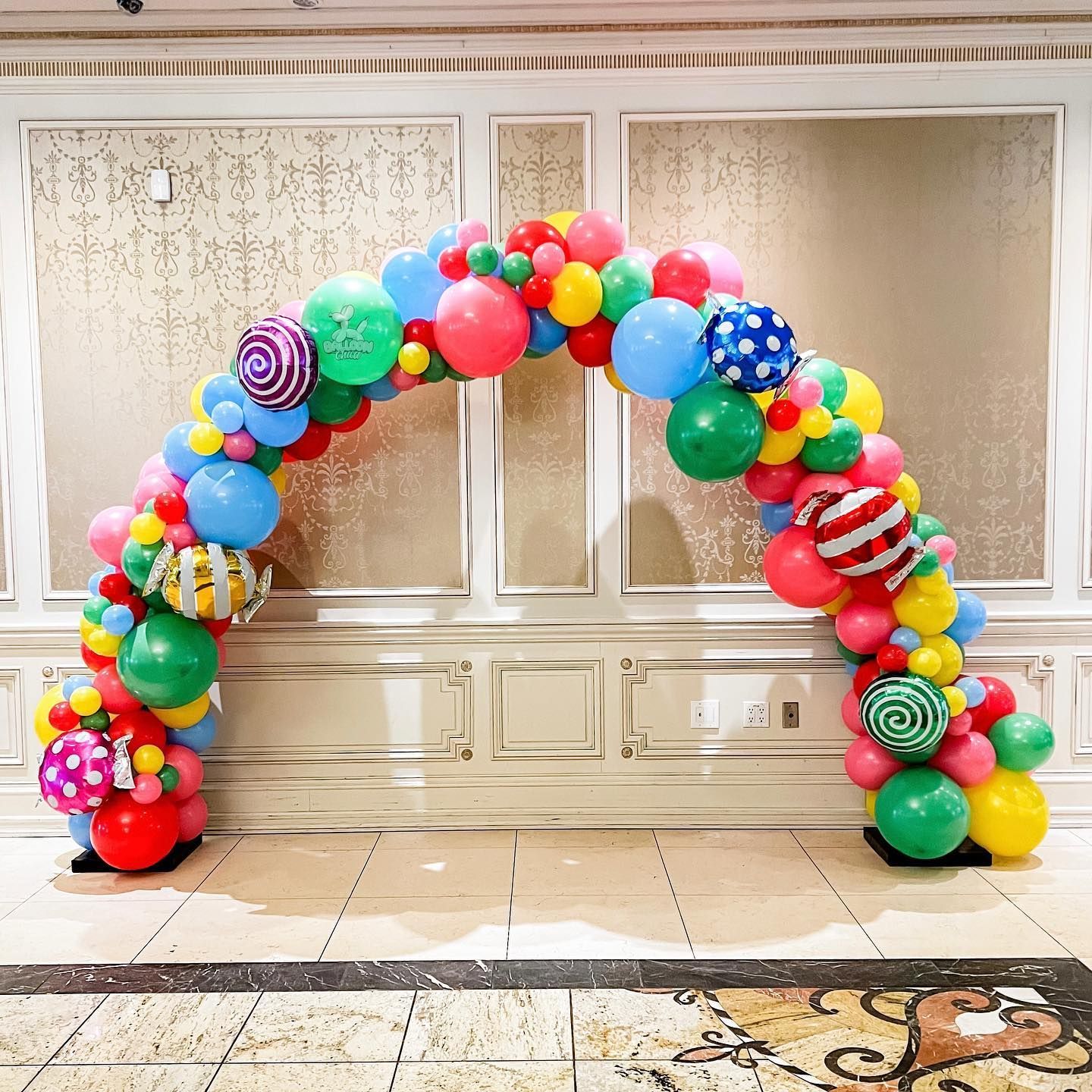 a large arch made of colorful balloons in a room