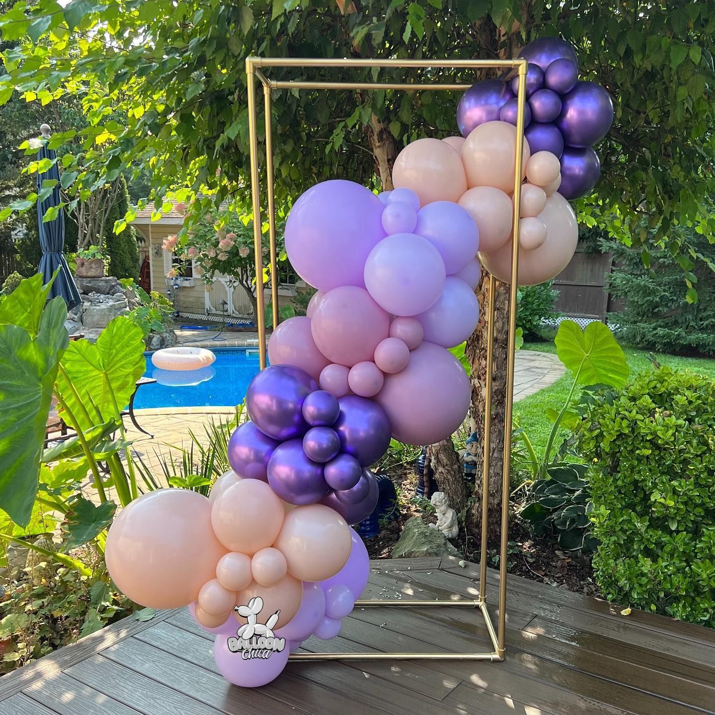 a bunch of balloons are sitting on a wooden deck in front of a pool