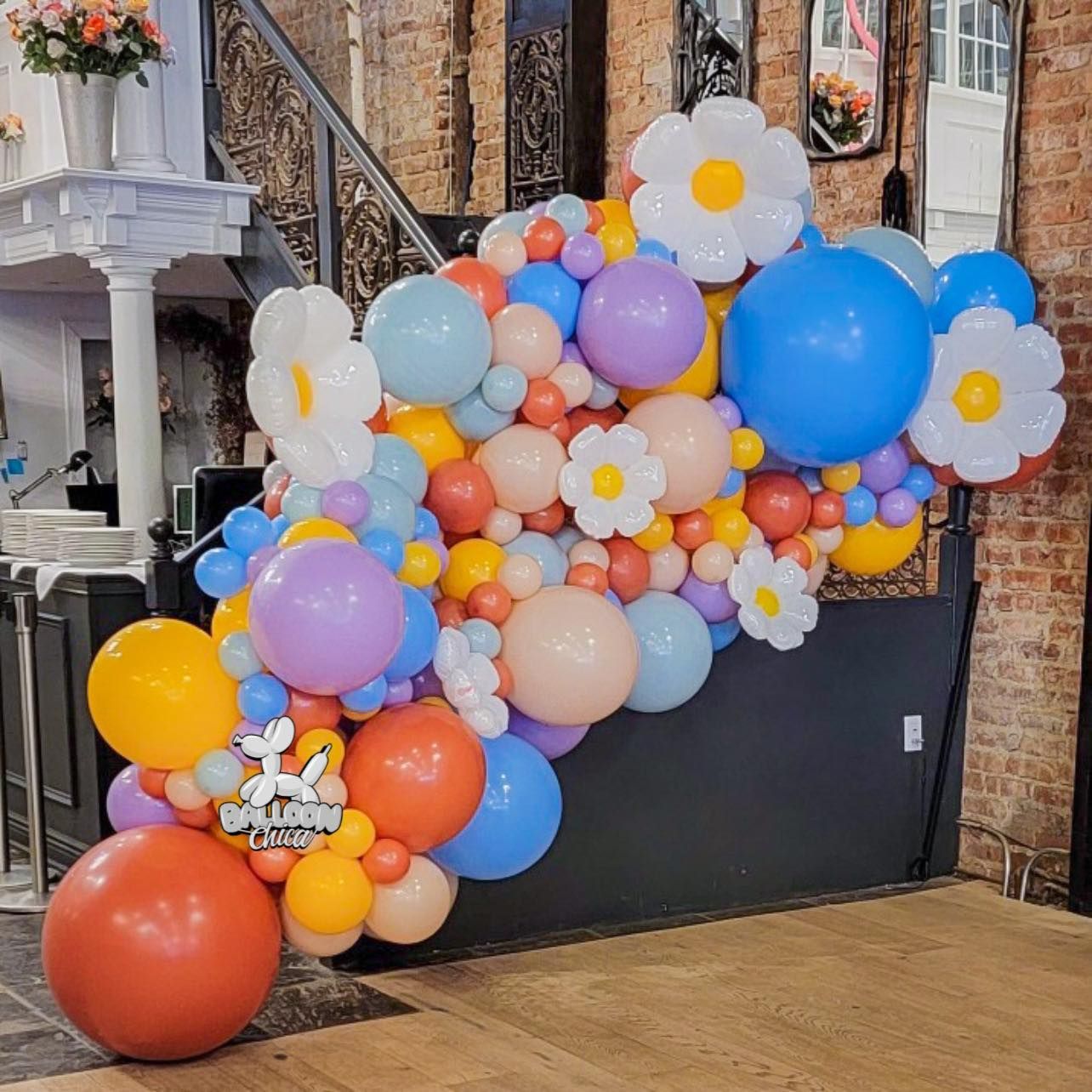 a bunch of colorful balloons and flowers in a room