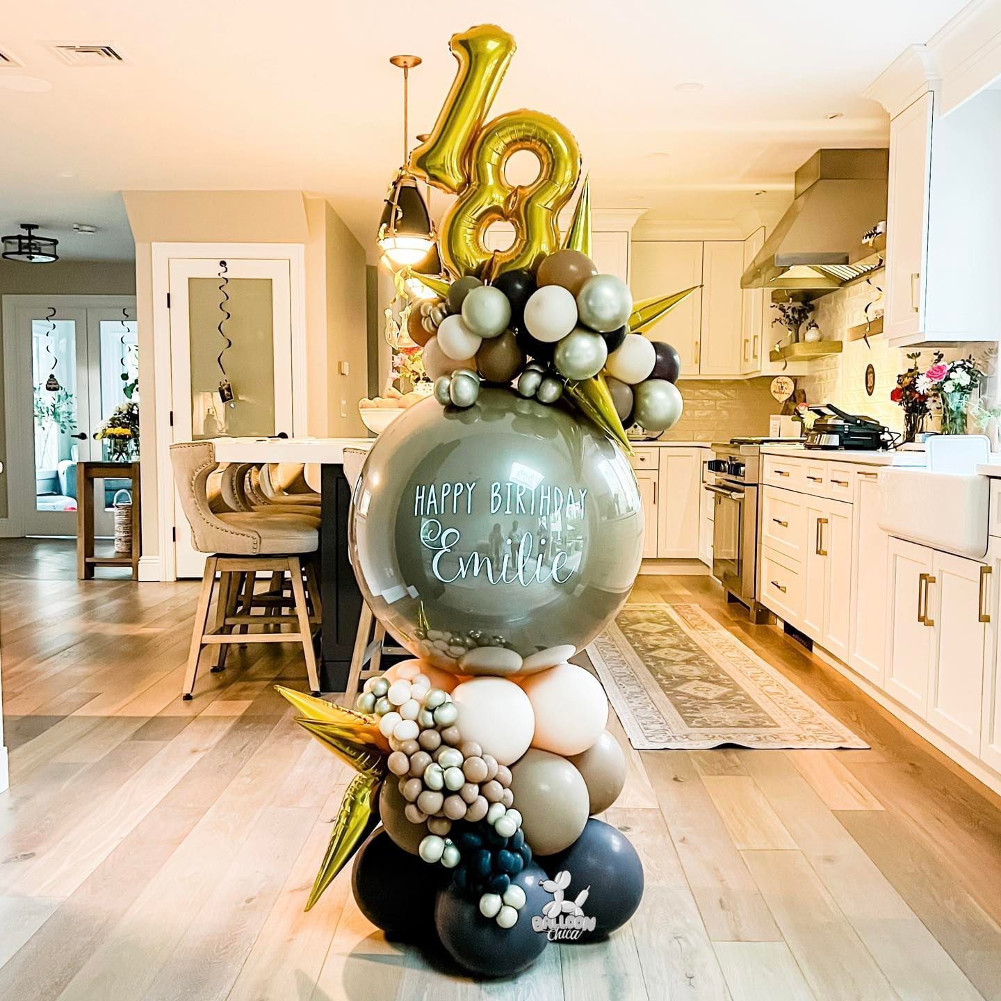 a bunch of balloons are sitting on a wooden floor in a kitchen