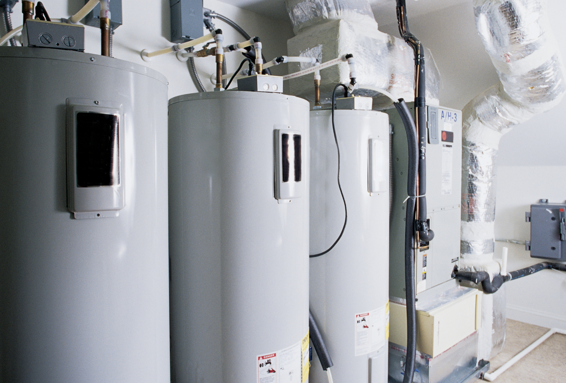 Three water heaters are sitting next to each other in a room.