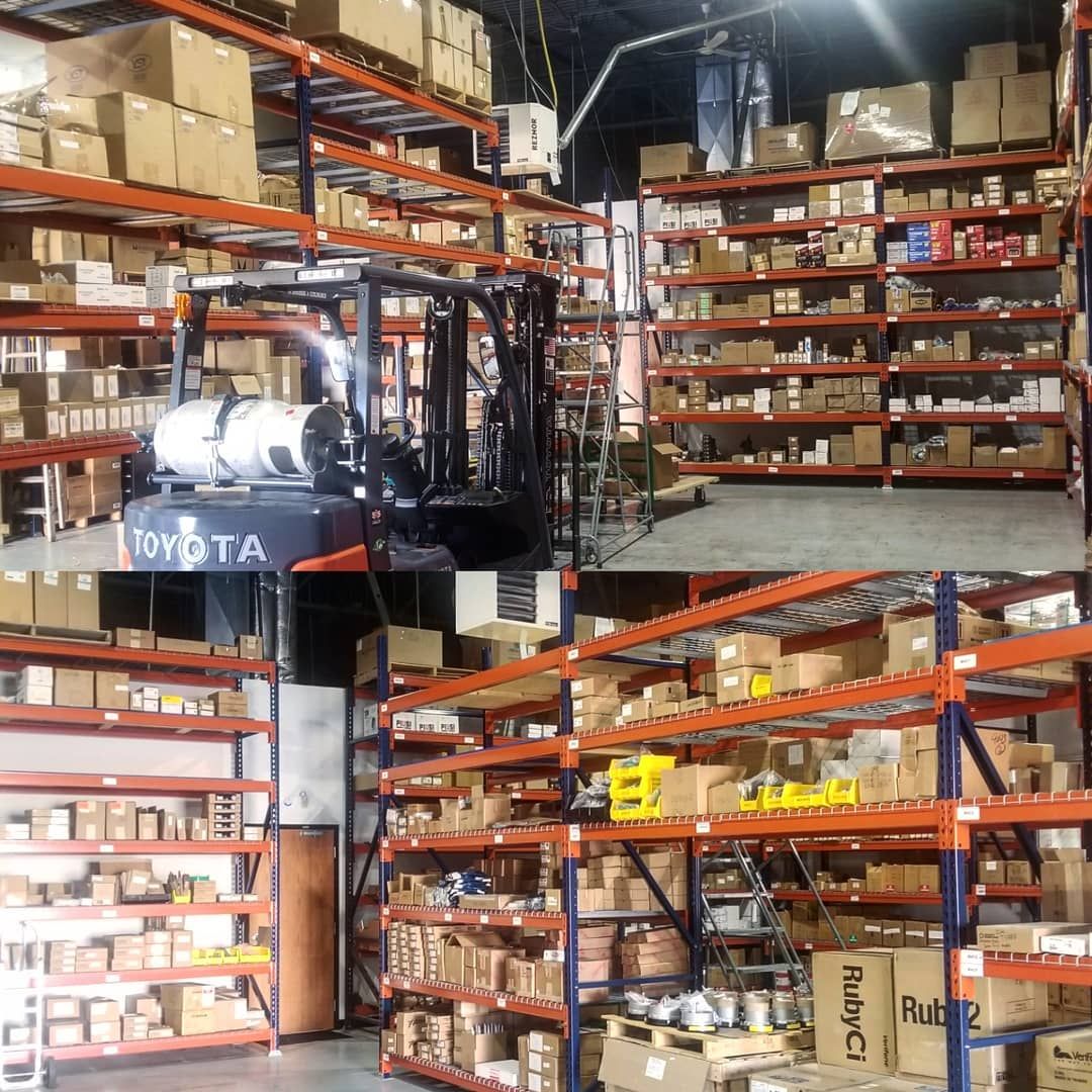 Warehouse interior with shelves of boxes, forklift, and a ladder. The Toyota forklift is near the center of the photo.