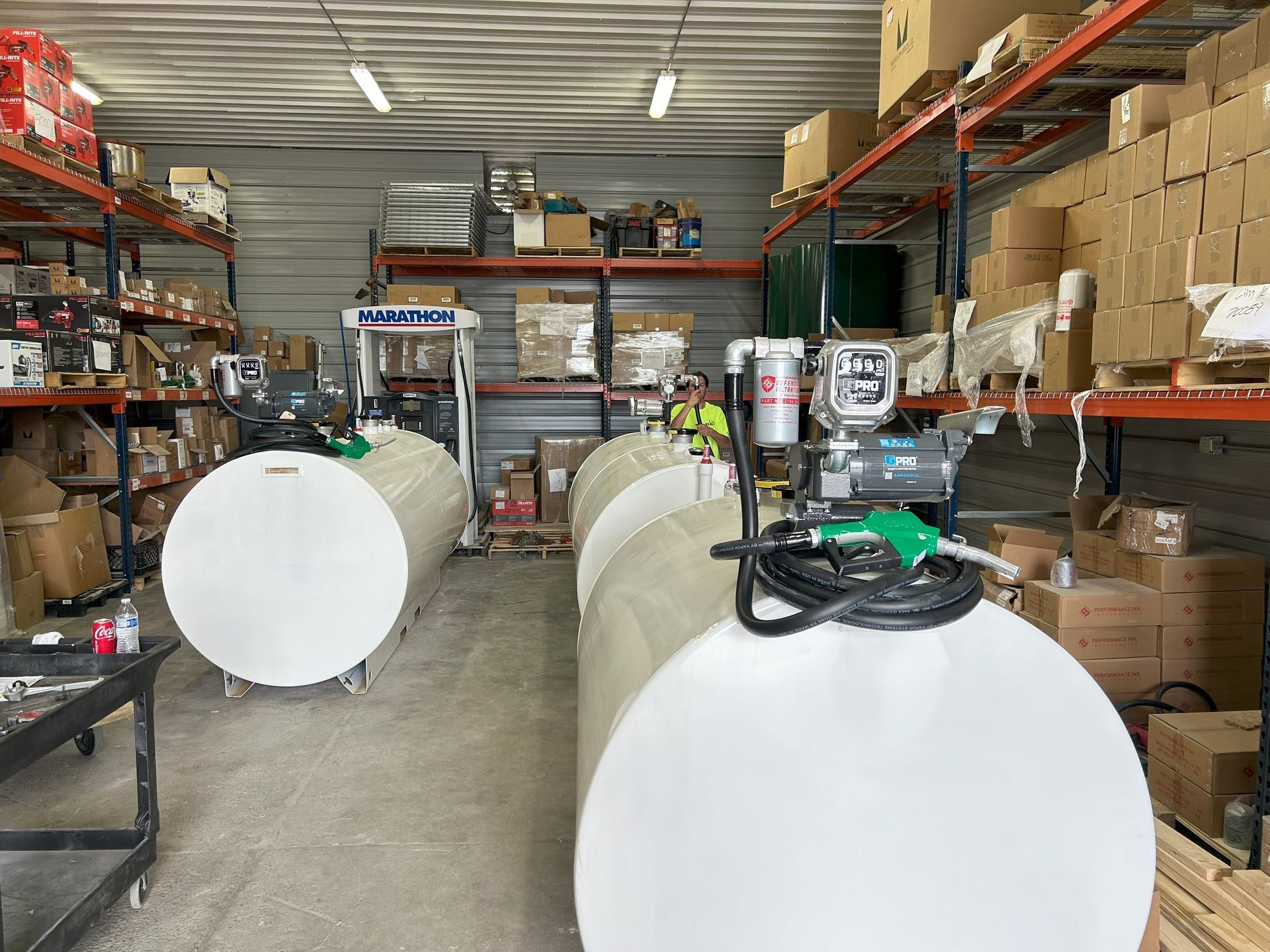 Fuel tanks with pumps inside a warehouse with shelves of boxes.