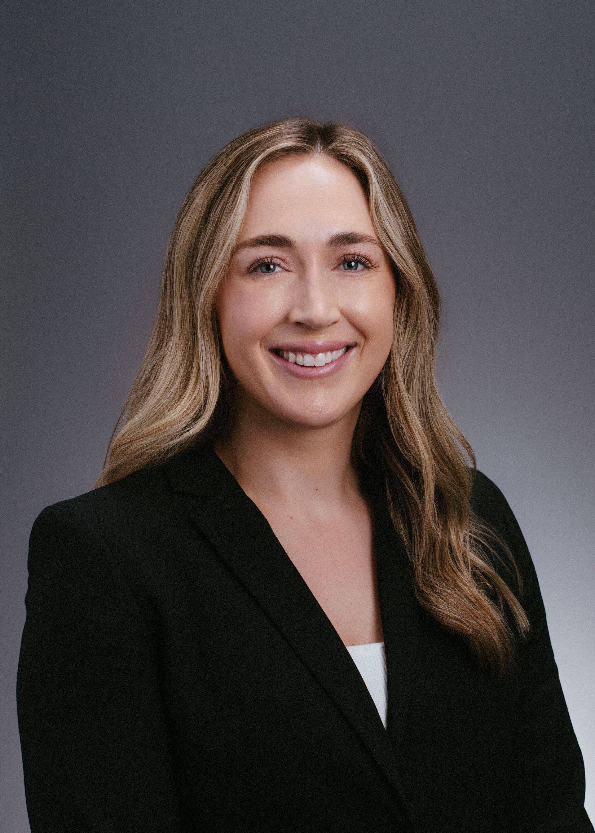 A woman in a black jacket is smiling for the camera.