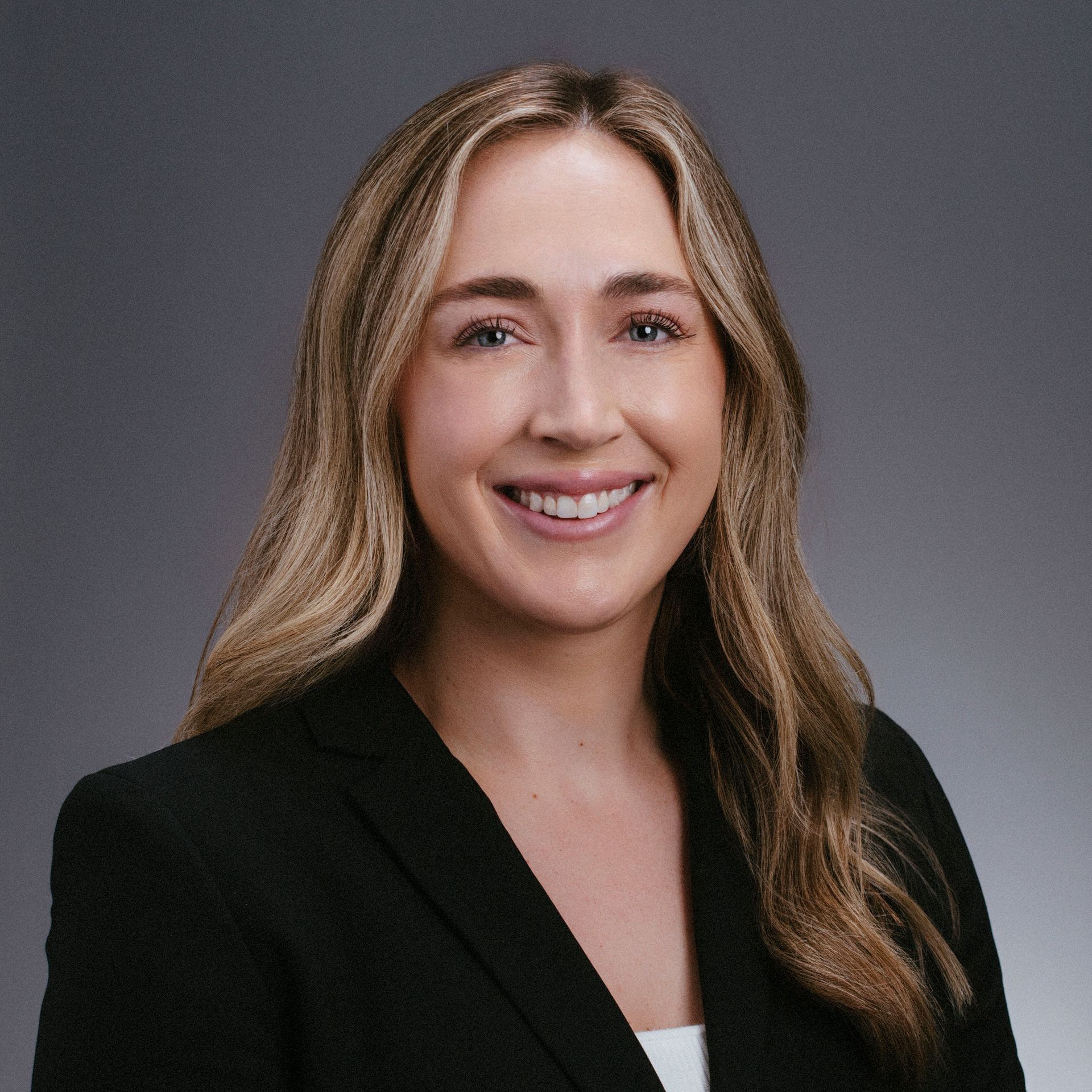 A woman in a black jacket is smiling for the camera.