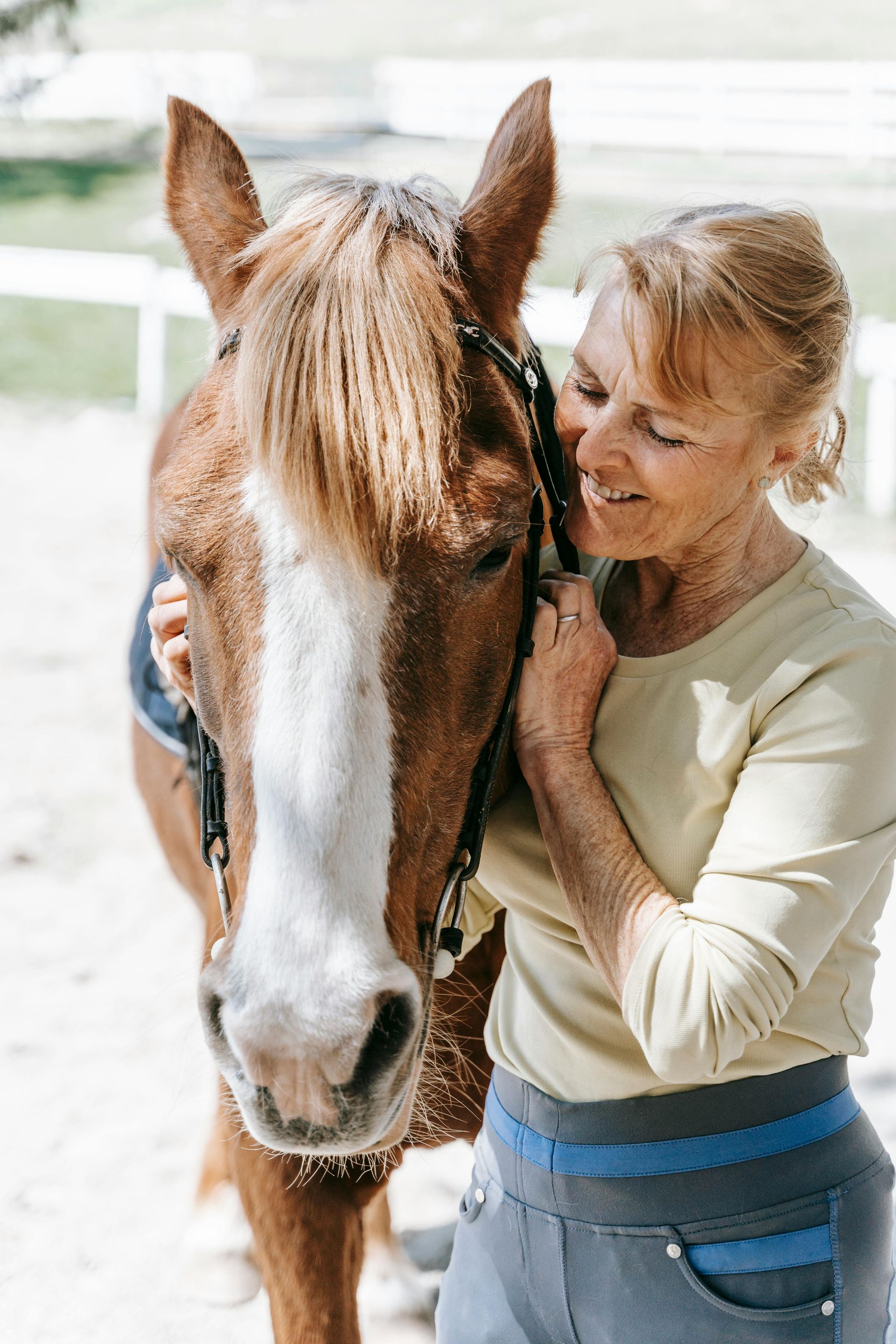 A woman is hugging a brown horse in a stable.