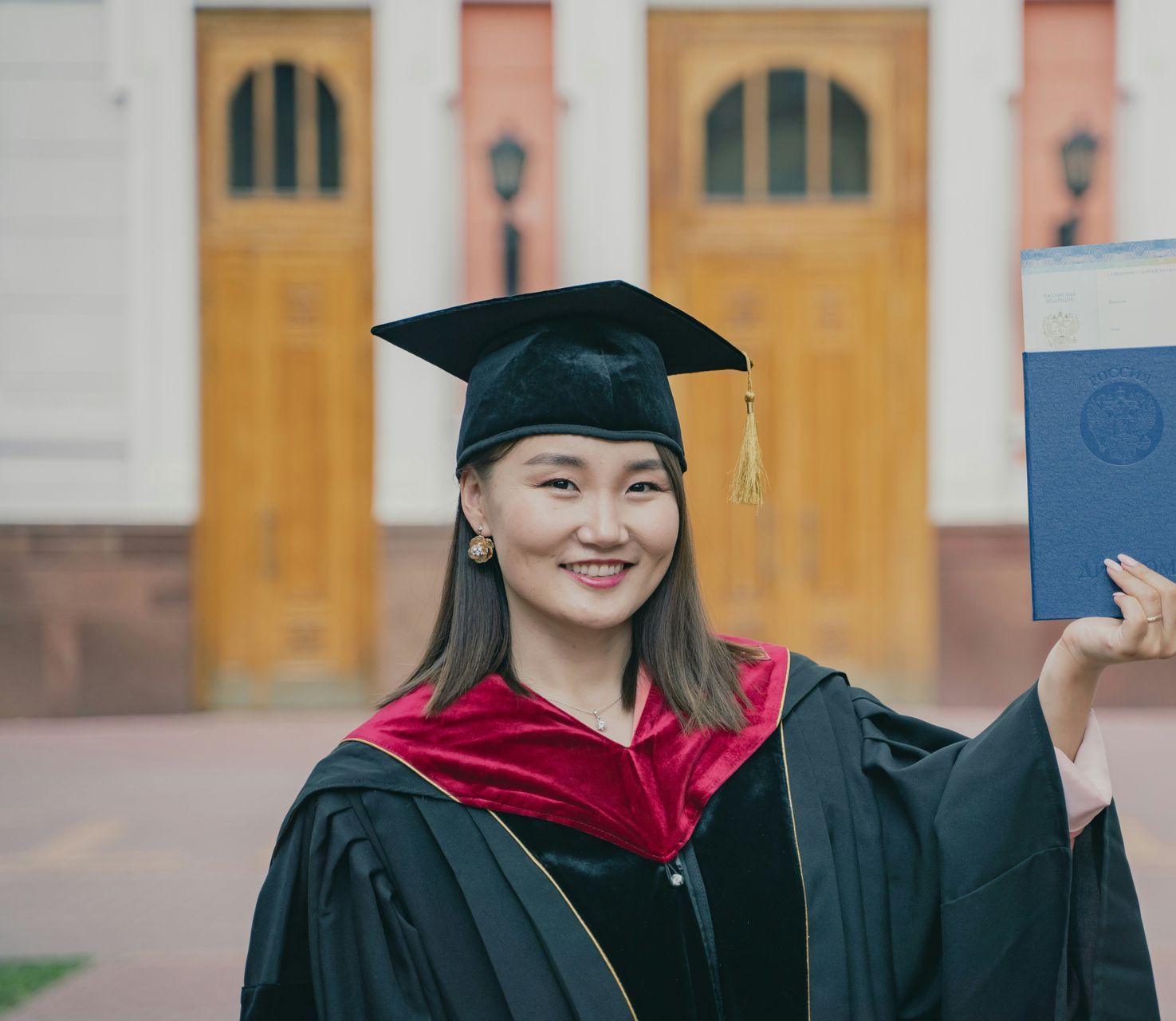 A woman in a graduation cap and gown is holding a diploma.