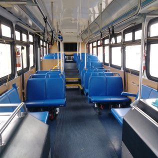 The inside of a bus with blue seats and stairs