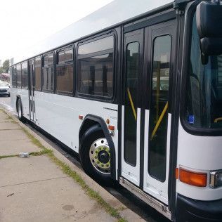 A white and black bus is parked on the side of the road.