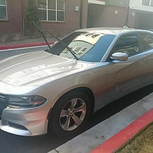 A silver dodge charger is parked on the side of the road.