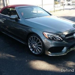 A mercedes convertible with a red top is parked on the side of the road.
