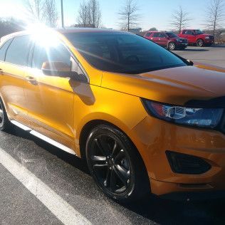 A yellow ford edge is parked in a parking lot.