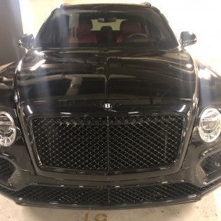 A black bentley bentayga is parked in a garage.