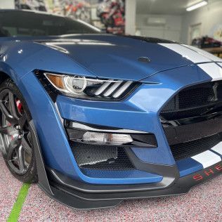 A blue and white ford mustang is parked in a garage.