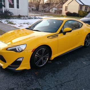 A yellow sports car is parked in front of a house.
