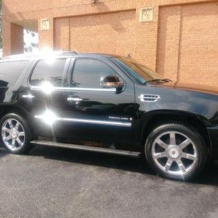 A black car is parked in front of a brick building.