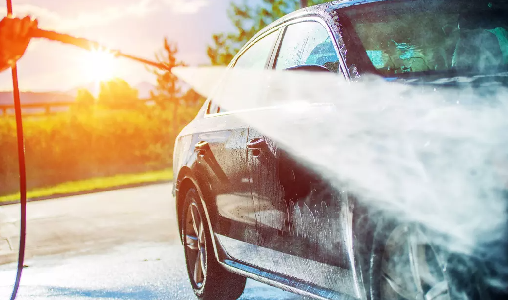 A person is washing a car with a high pressure washer.