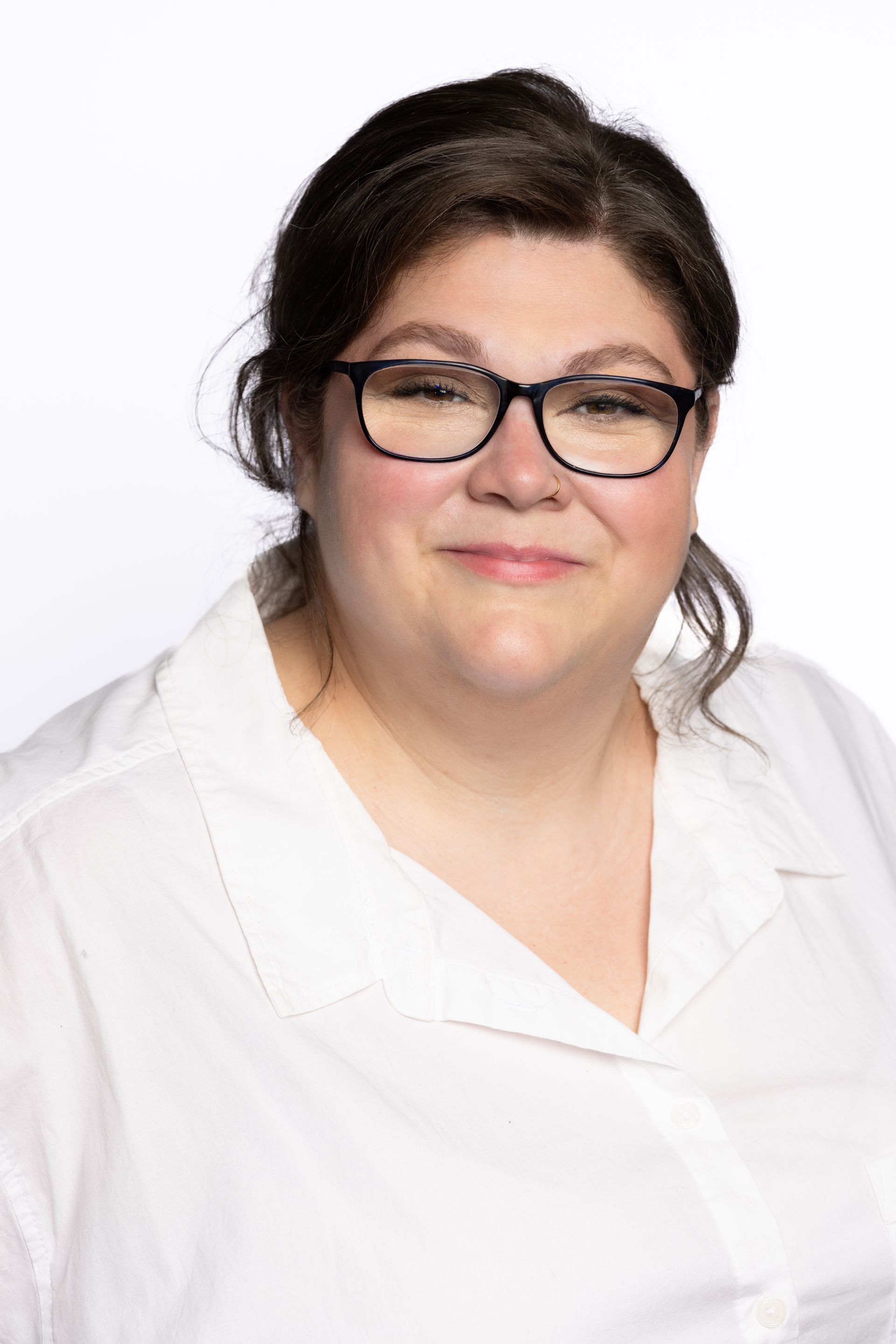 Woman wearing glasses and white shirt, smiling against a white background.