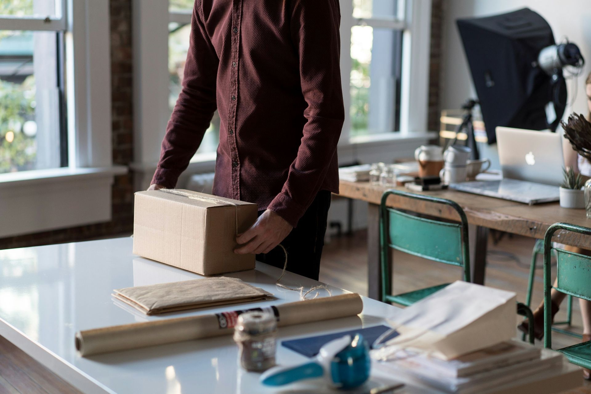 A man is standing next to a table holding a cardboard box.