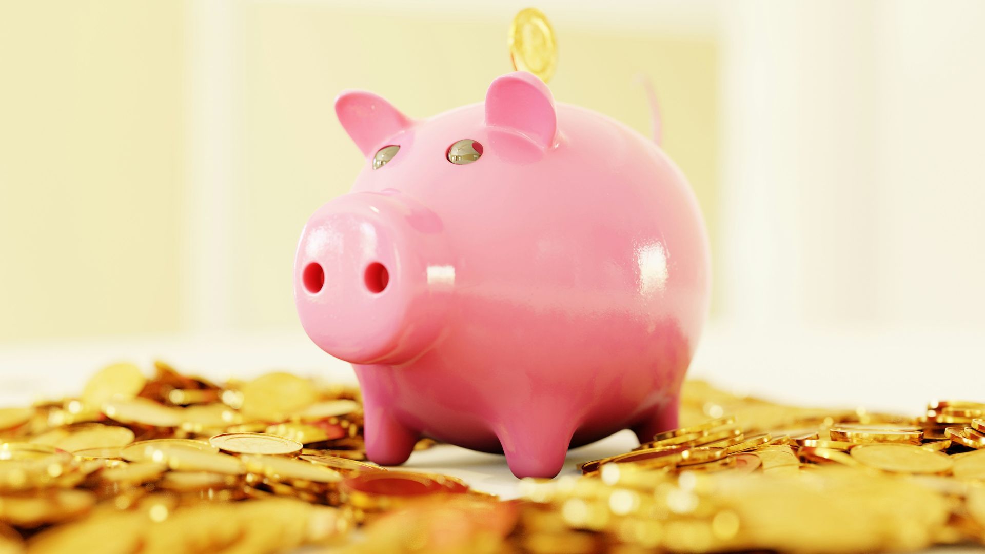 A pink piggy bank is sitting on top of a pile of gold coins.