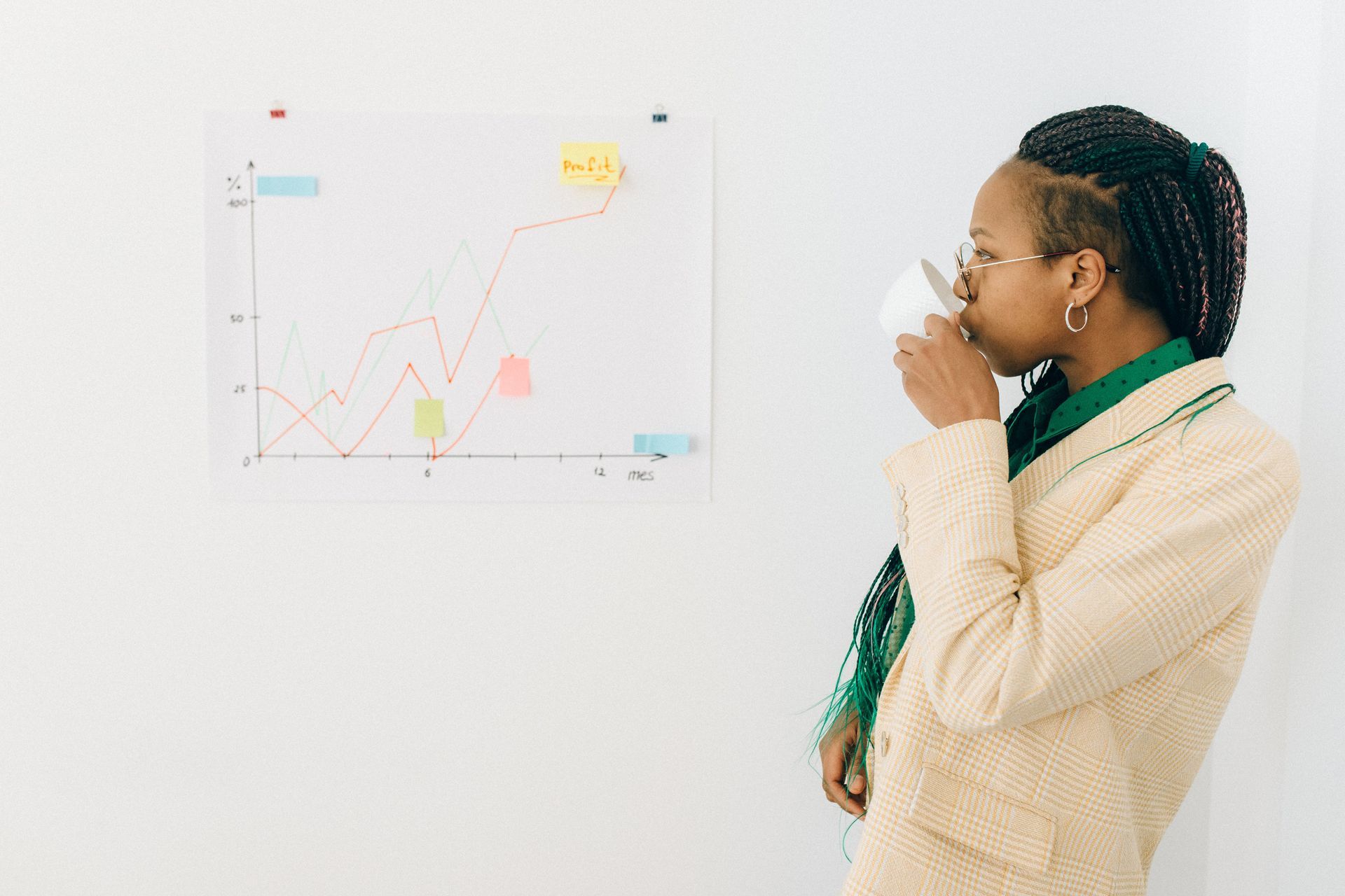 A woman is drinking coffee in front of a whiteboard with a graph on it.