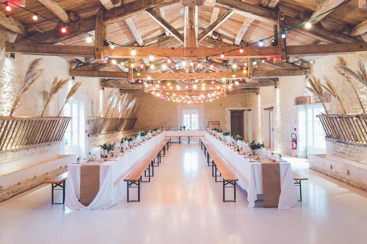 Una gran sala con mesas y bancos preparados para una recepción de boda. | Fonrecar. Organizadores de eventos