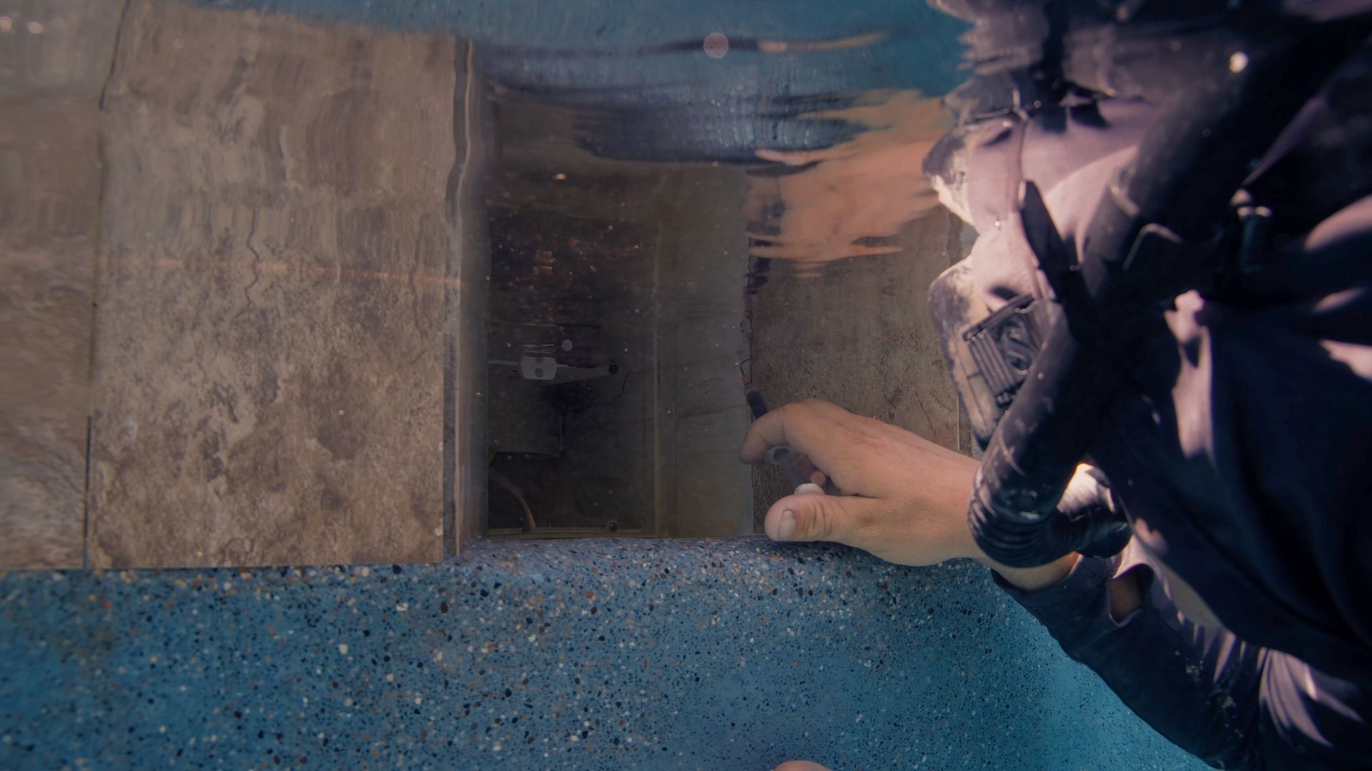 Scuba diver inspecting a pool's underwater structure.