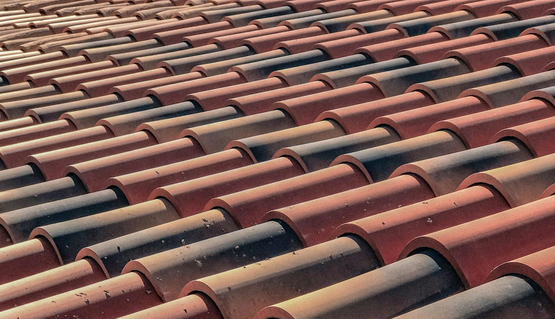 A close up of a row of red and black tiles on a roof.