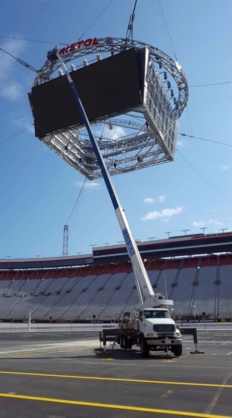 A large screen is being lifted into the air by a crane.