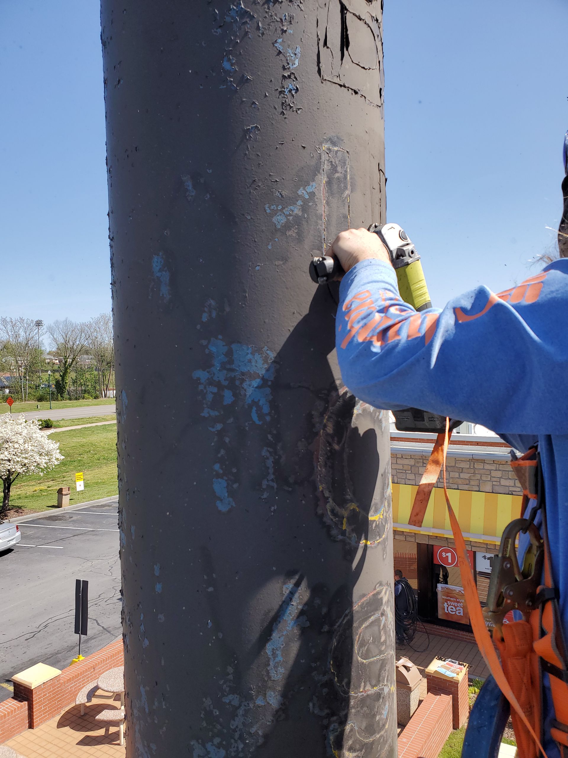 A man in a blue shirt is working on a pole