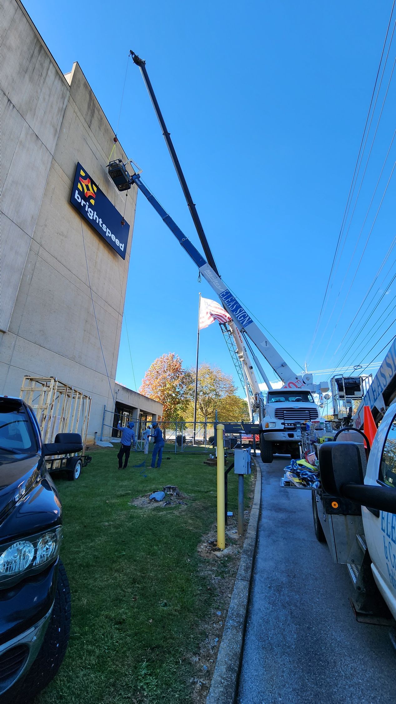 A large crane is lifting a sign on the side of a building.