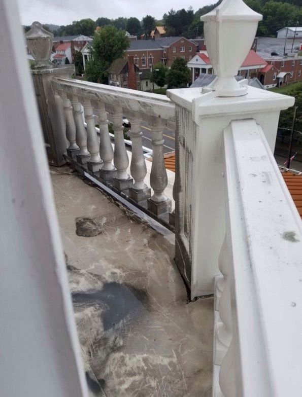 A balcony with a white railing and a lamp post.