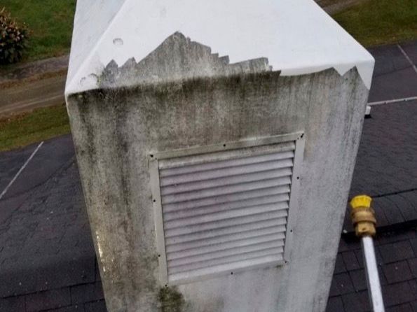 A dirty chimney on top of a roof next to a hose.